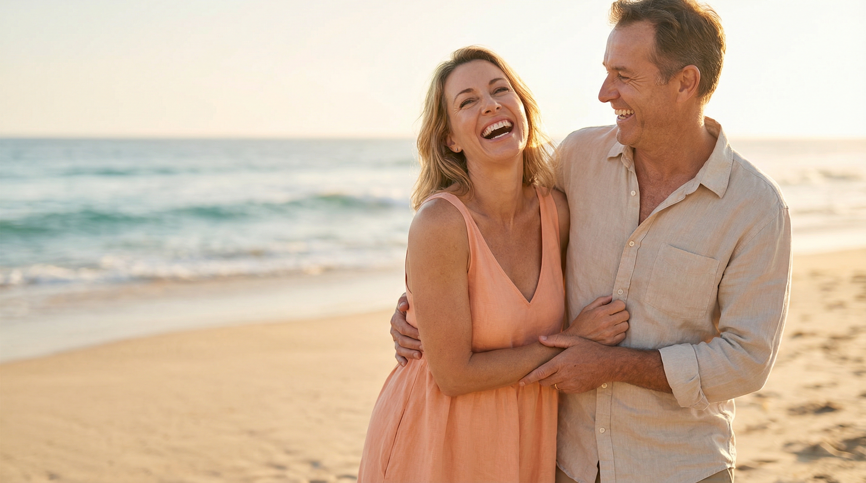 Happy couple laughing at the beach, representing vitality after menopause treatment